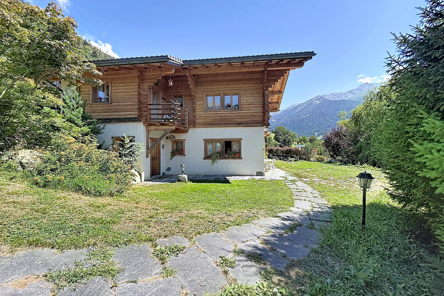 Jardin engazonné avec chemin de dalles menant au chalet.