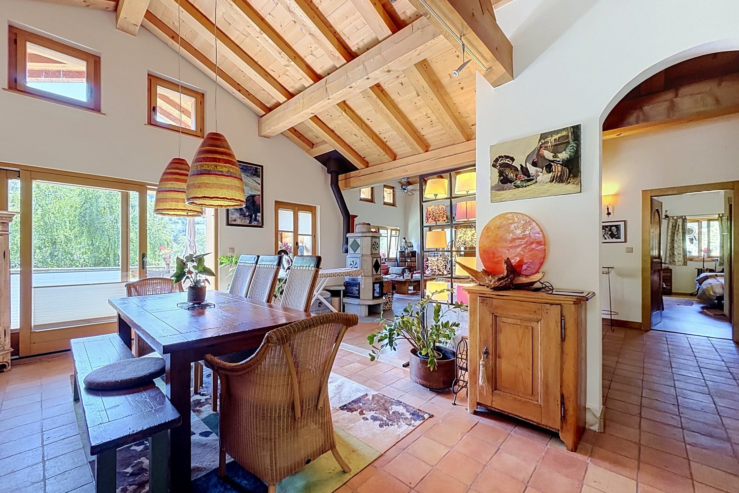 Salle à manger avec table et bancs de bois, arcs ouverts sur le reste de l'étage.