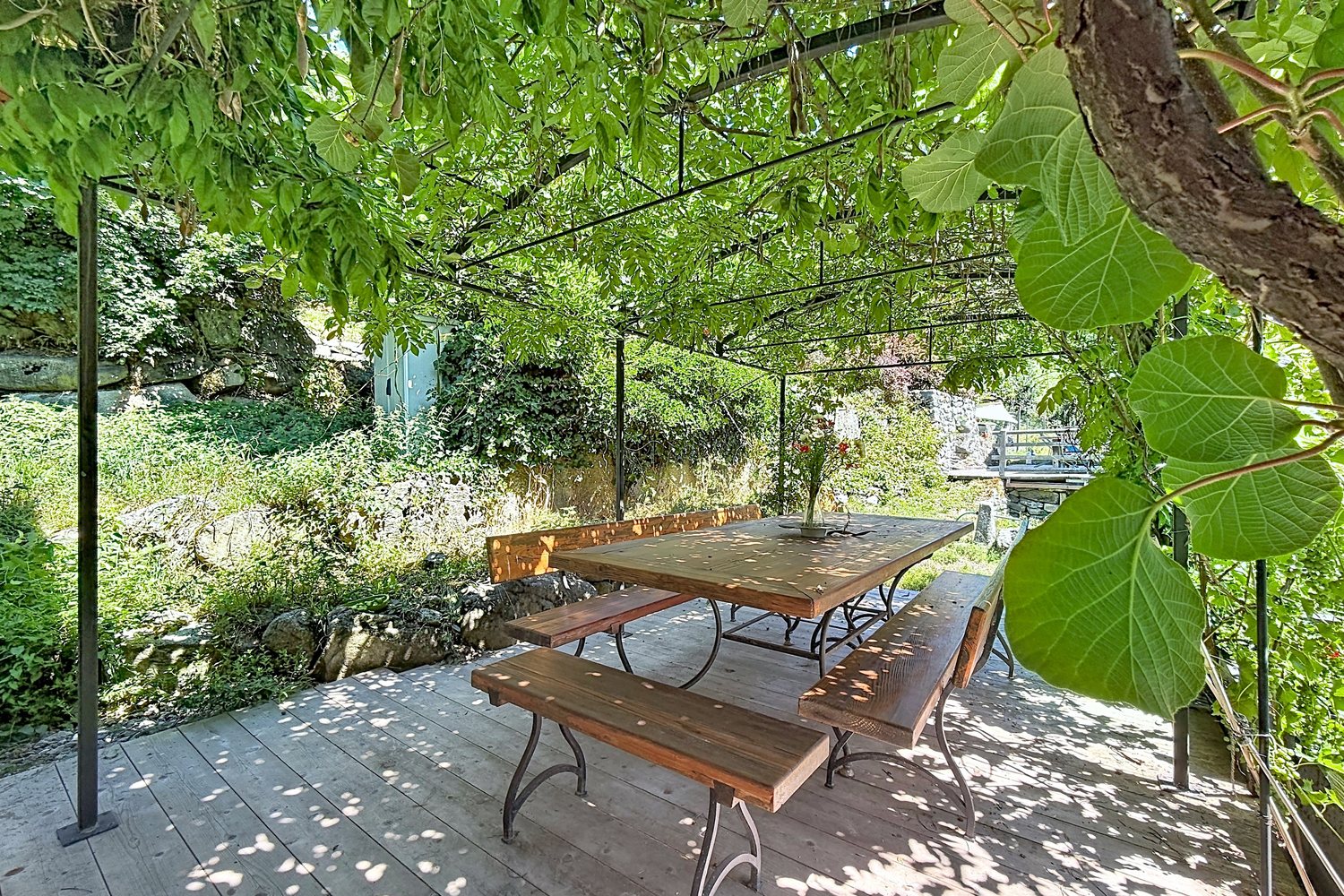 Table d'été sous une treille végétale, dans le jardin en terrasses.